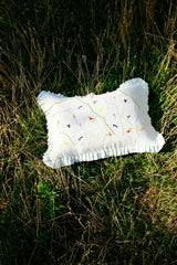 grey pillow with colorful patterns on grass