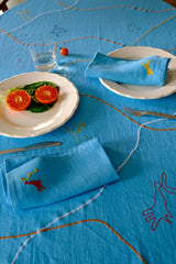 Blue tablecloth with embroidered designs and a plate of food on a table.