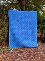 Blue quilted cover on a mattress outdoors with trees in the background