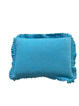 Blue pillow with ruffled edges on a white background