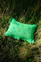 Green pillow with embroidered designs on grass