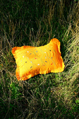 Asafo orange cushion  with embroidery on a grassy background