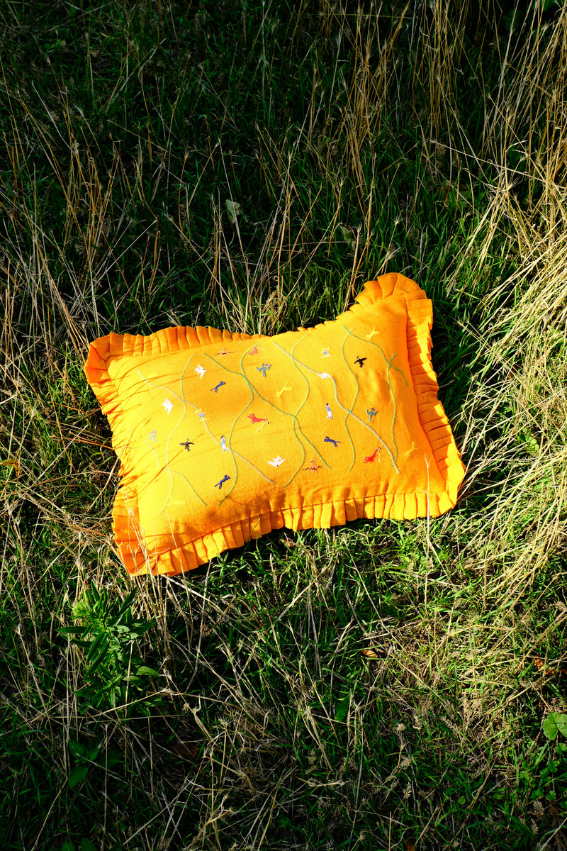 Asafo orange cushion  with embroidery on a grassy background