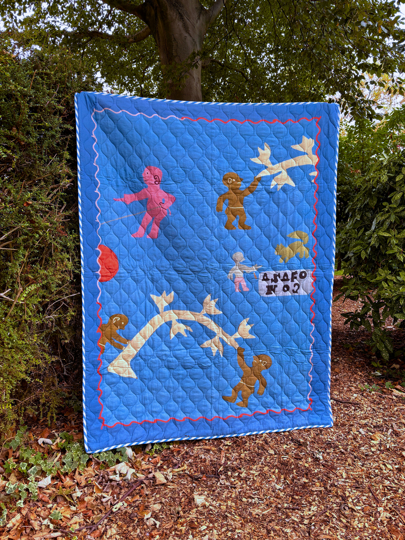 Asafo Blue quilt with colorful appliqué designs of children and animals, displayed outdoors.