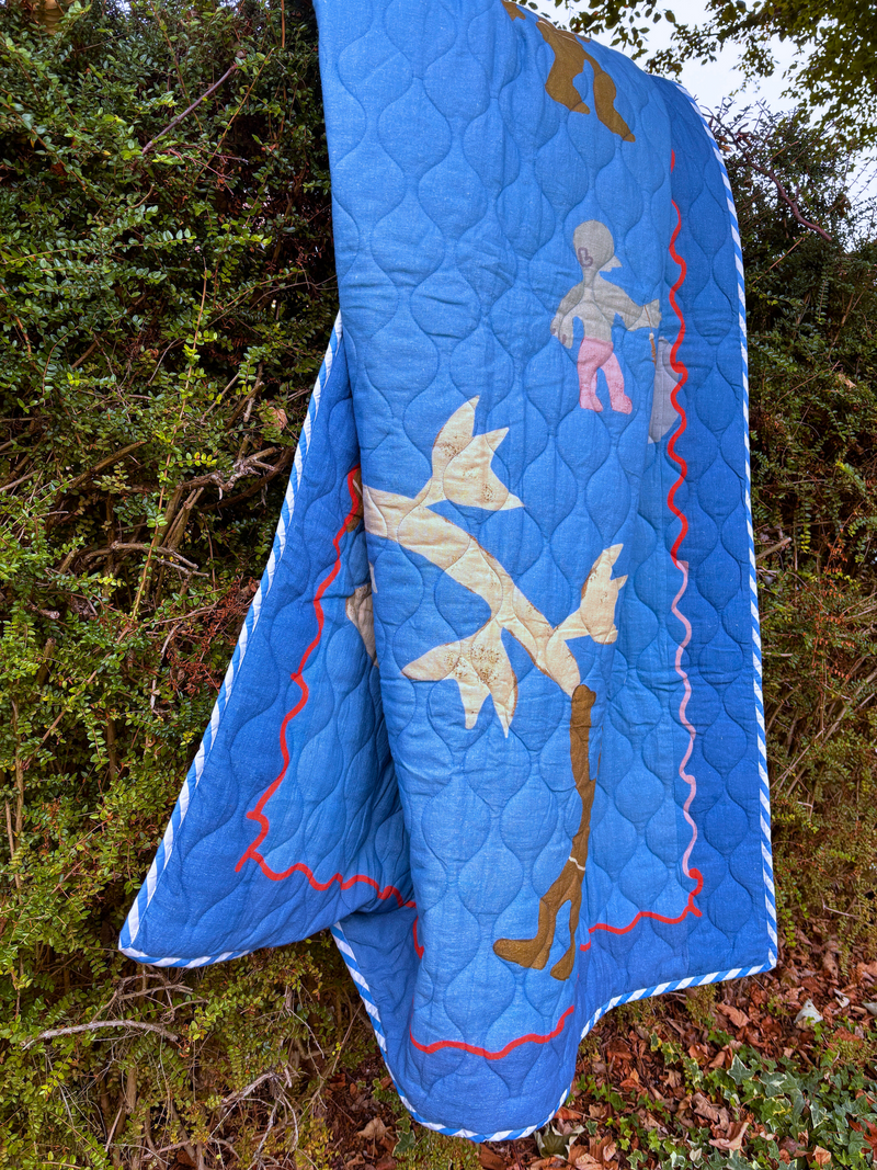 Asafo Blue quilt with airplane and playful tree climbers design draped over a tree