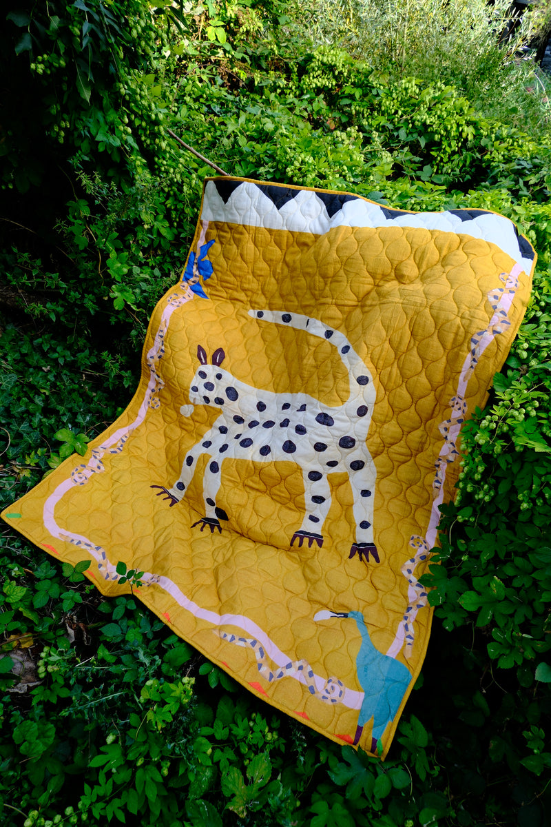 Quilt with a leopard design on a green grass background